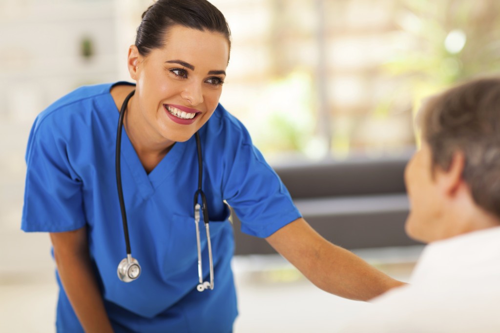 friendly young nurse talking to senior patient